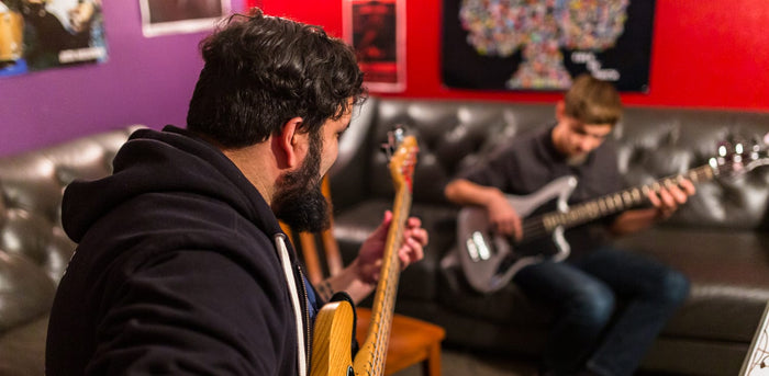 An instructor teaching guitar lessons to a young student. They are having a good time